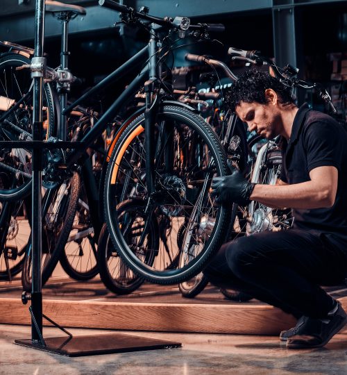 expirienced young master is repairing customer's bicycle at workplace