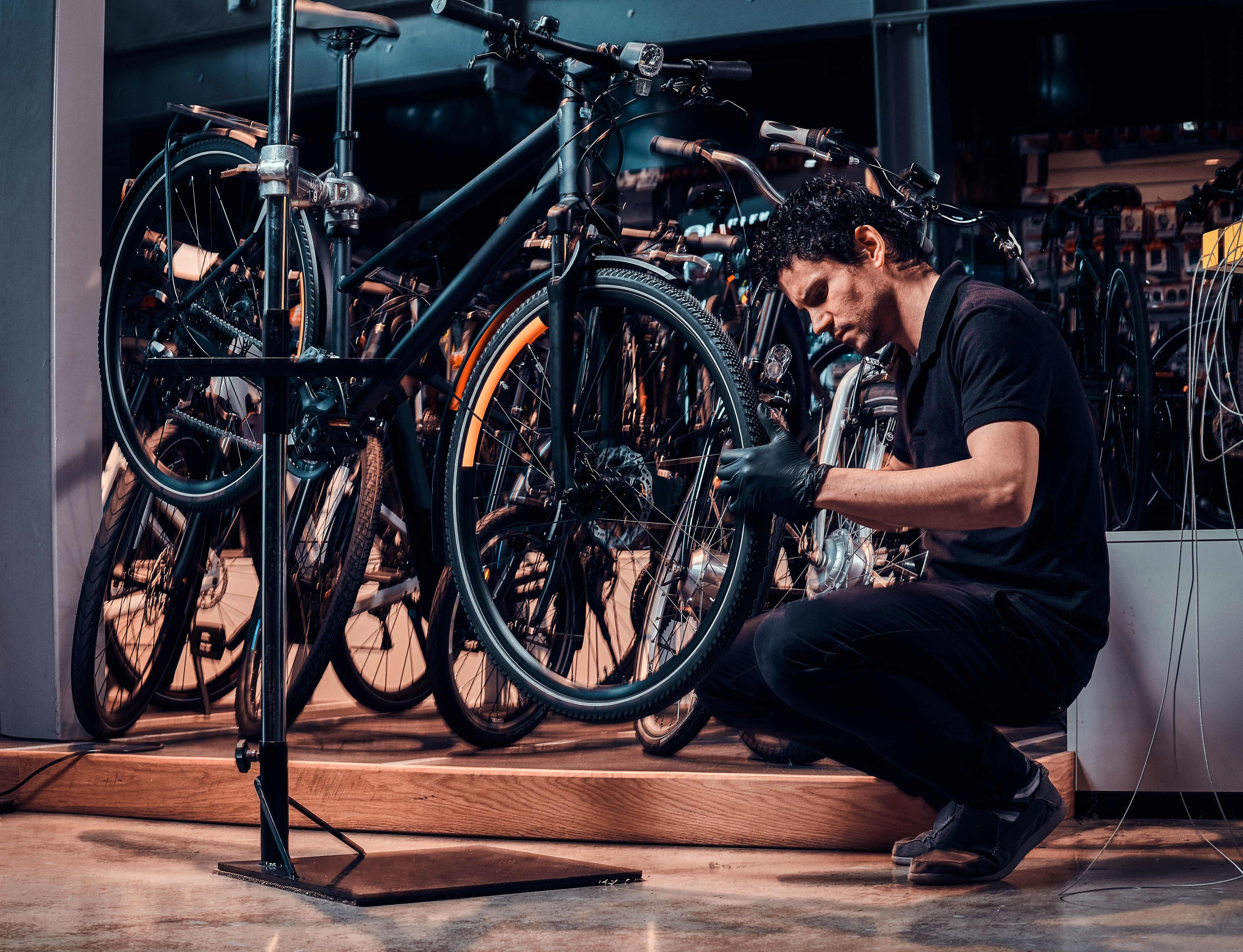 expirienced young master is repairing customer's bicycle at workplace