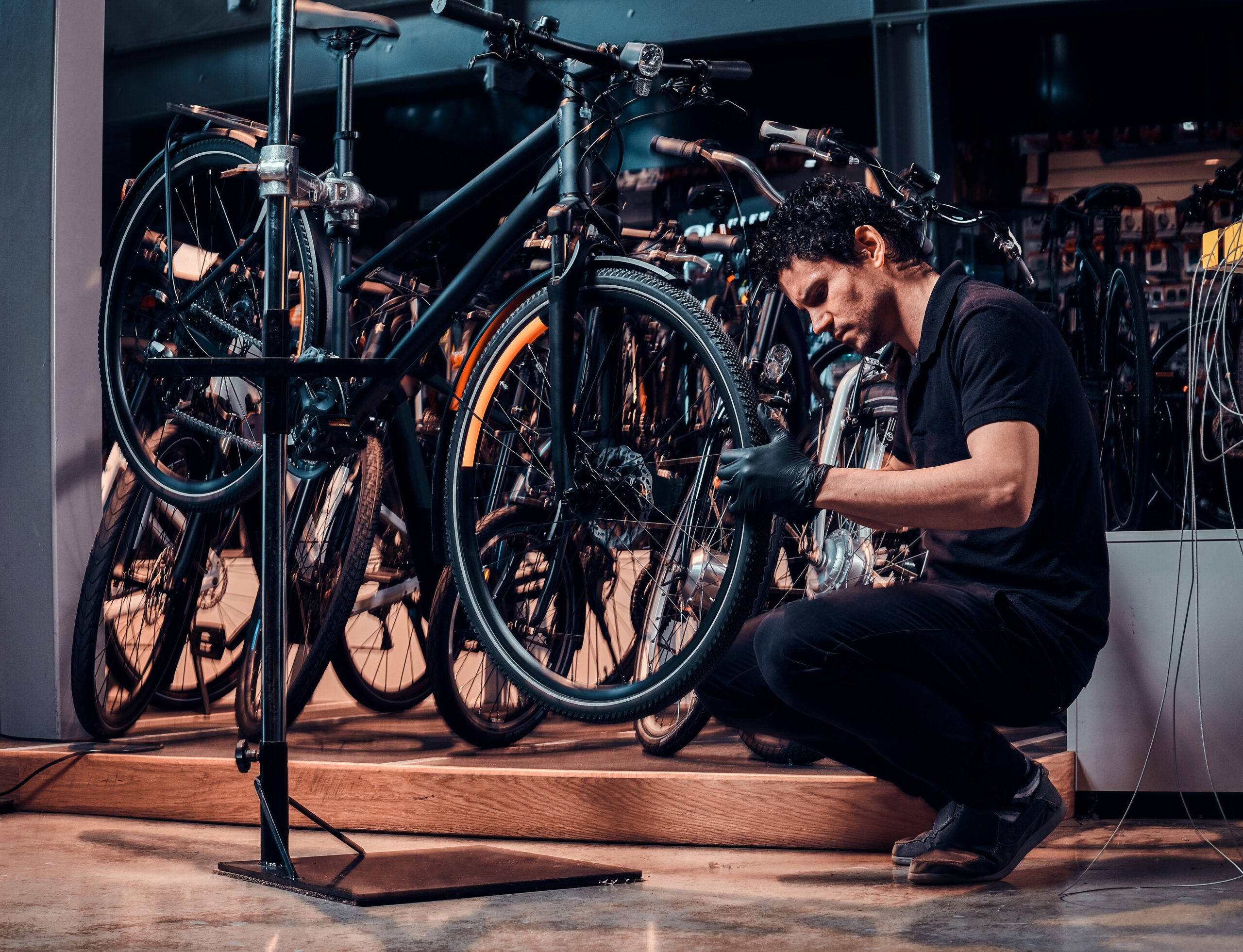 expirienced young master is repairing customer's bicycle at workplace